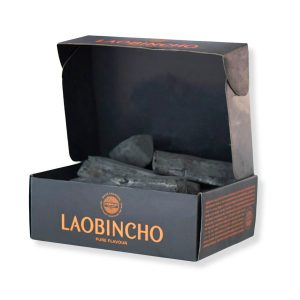 Box of black charcoal set against a white background, emphasizing the contrast between the dark charcoal and the light color.